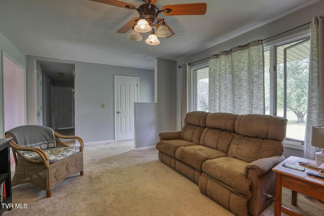 carpeted living area with baseboards, a ceiling fan, and a textured ceiling