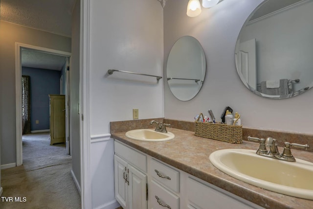full bathroom with baseboards, double vanity, and a sink