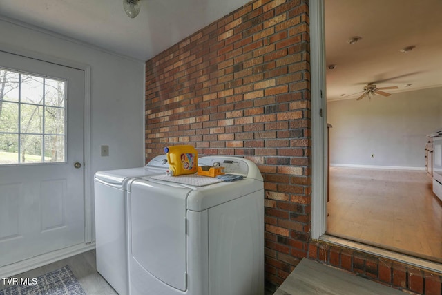 clothes washing area with baseboards, washer and dryer, brick wall, a ceiling fan, and laundry area