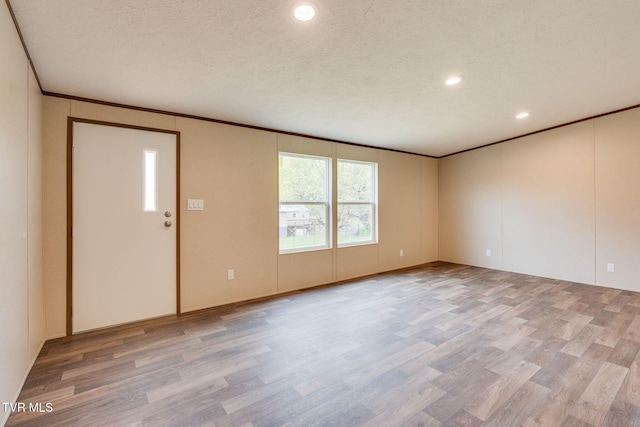 interior space with crown molding, light wood finished floors, and a textured ceiling