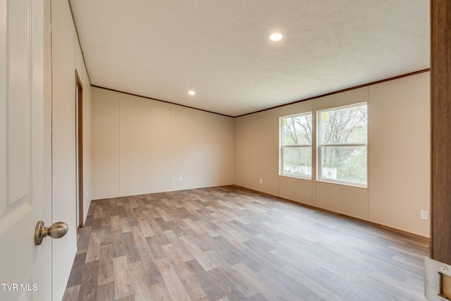 empty room featuring recessed lighting, light wood finished floors, a textured ceiling, and ornamental molding