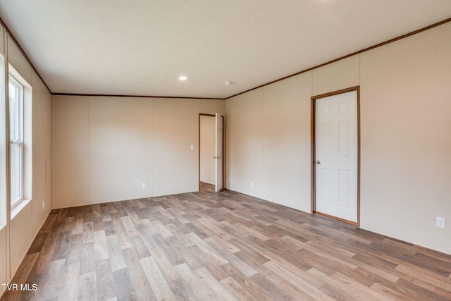 unfurnished room with light wood-type flooring and ornamental molding