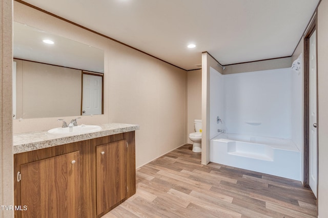 bathroom featuring vanity, a tub, recessed lighting, toilet, and wood finished floors