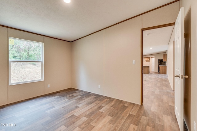 spare room featuring ornamental molding, light wood-style floors, and a textured ceiling