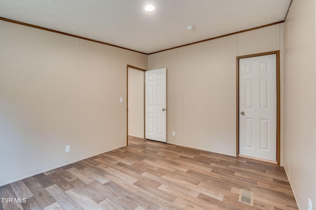 empty room featuring visible vents, crown molding, and light wood-style flooring