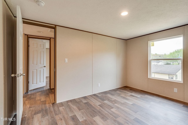 unfurnished room with light wood-style floors and a textured ceiling