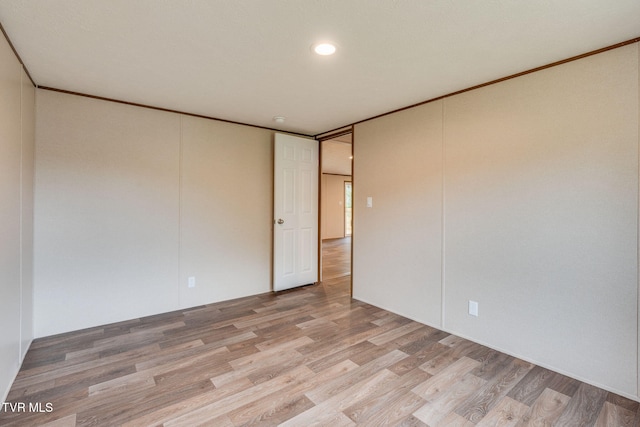 spare room featuring light wood finished floors and ornamental molding