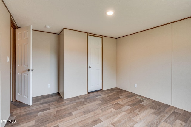 unfurnished bedroom with light wood finished floors and ornamental molding