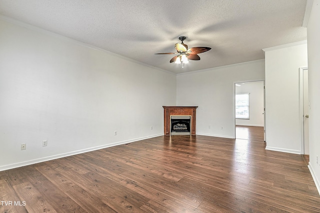 unfurnished living room featuring ornamental molding, a ceiling fan, a textured ceiling, a fireplace, and dark wood-style floors