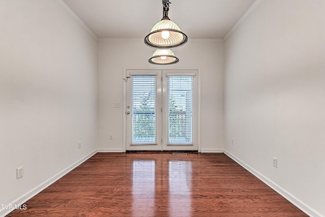 spare room with ornamental molding, baseboards, and dark wood finished floors