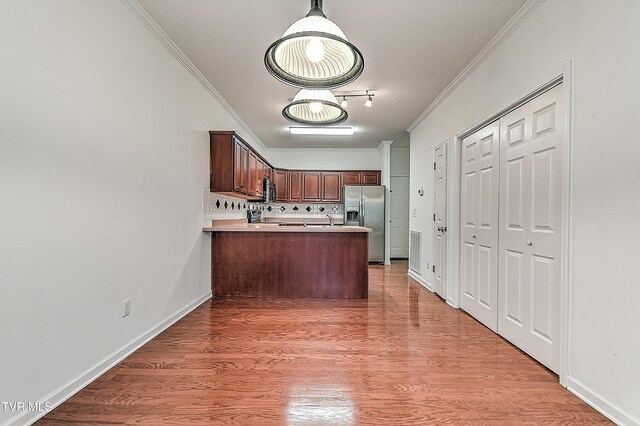 kitchen featuring a peninsula, crown molding, light wood-type flooring, and stainless steel appliances