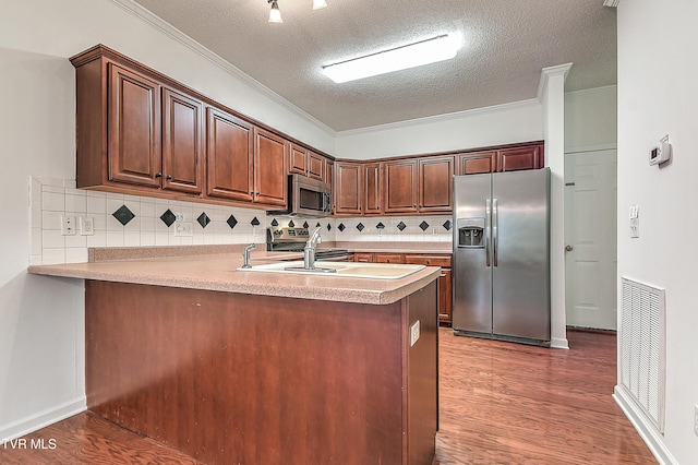 kitchen with a peninsula, visible vents, wood finished floors, and appliances with stainless steel finishes