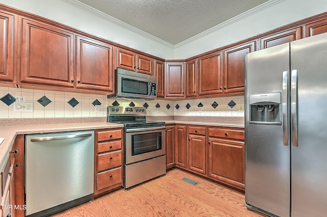 kitchen featuring crown molding, a textured ceiling, light countertops, stainless steel appliances, and decorative backsplash