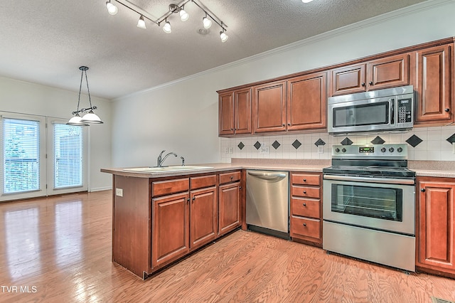 kitchen with light wood-type flooring, a peninsula, light countertops, a textured ceiling, and stainless steel appliances