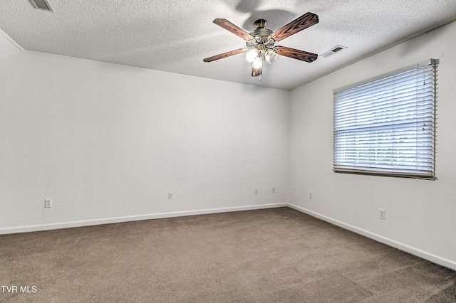 carpeted empty room featuring a textured ceiling, ceiling fan, baseboards, and visible vents