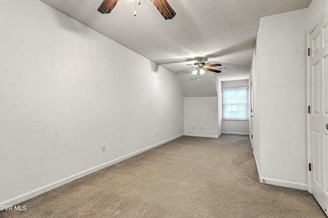 interior space featuring baseboards, a ceiling fan, light carpet, and a textured ceiling