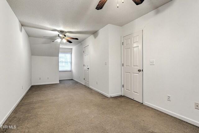 carpeted spare room featuring a textured ceiling, baseboards, and ceiling fan