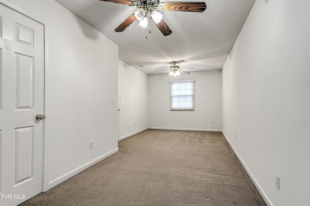 empty room with ceiling fan, light colored carpet, baseboards, and a textured ceiling