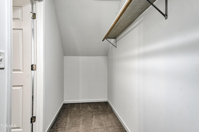 spacious closet with dark colored carpet and lofted ceiling