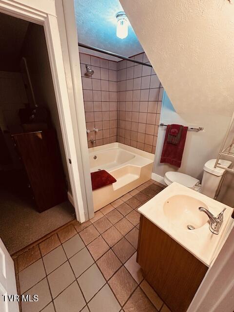 bathroom with toilet, a textured ceiling,  shower combination, vanity, and tile patterned floors