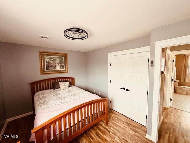 bedroom featuring visible vents, a closet, baseboards, and wood finished floors