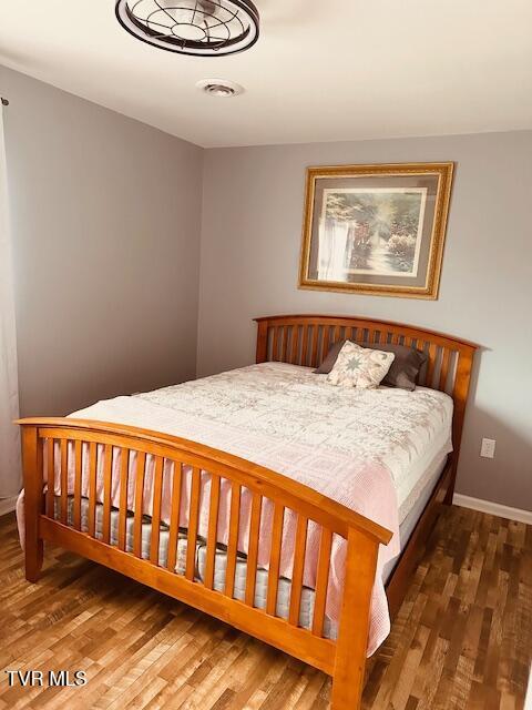 bedroom with visible vents, baseboards, and wood finished floors
