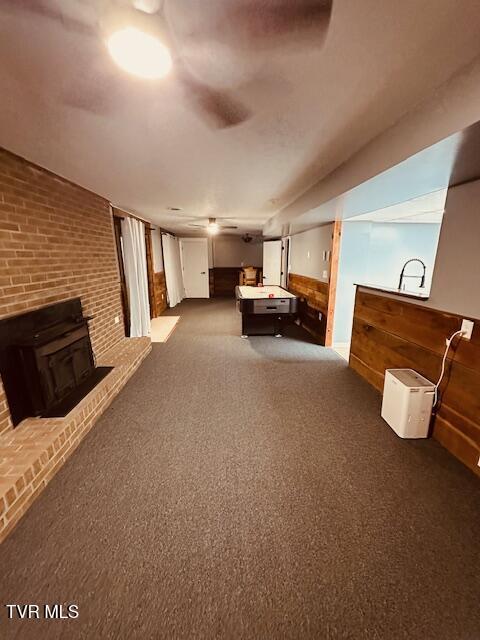 carpeted bedroom with wooden walls, a wood stove, billiards, and brick wall