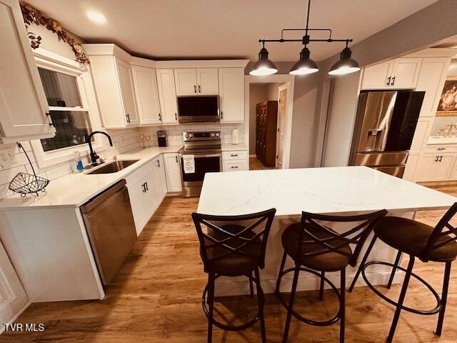 kitchen featuring a breakfast bar, backsplash, a kitchen island, appliances with stainless steel finishes, and a sink