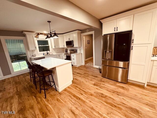 kitchen featuring a sink, light countertops, light wood-type flooring, appliances with stainless steel finishes, and white cabinetry