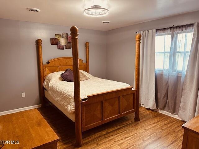 bedroom featuring visible vents, light wood-style flooring, and baseboards