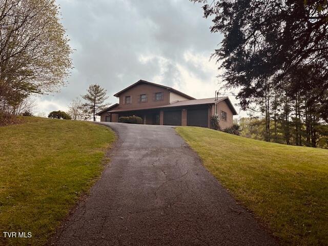 view of front of home with an attached garage, aphalt driveway, and a front lawn