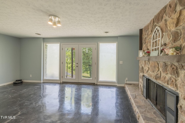 916 New Beason Well Rd, Kingsport, TN 37660 - unfurnished living room with a stone fireplace, finished concrete flooring, a textured ceiling, baseboards, and french doors