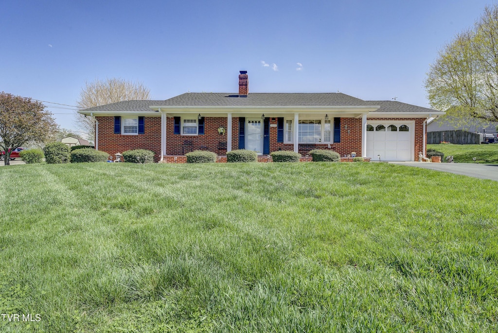 single story home with concrete driveway, brick siding, a garage, and a front lawn