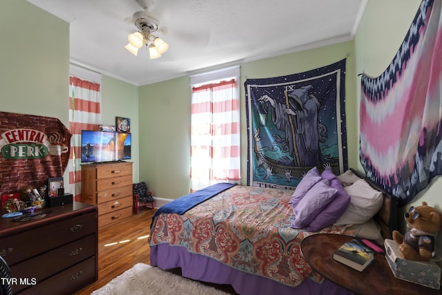 bedroom with wood finished floors, a ceiling fan, and ornamental molding
