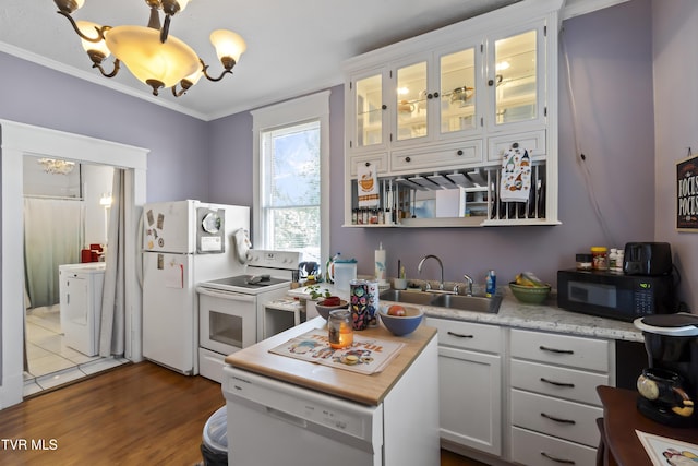 kitchen with a sink, light countertops, dark wood-style flooring, ornamental molding, and white appliances