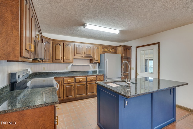 120 Lynnwood Dr, Johnson City, TN 37615 - kitchen with light tile patterned floors, a sink, an island with sink, brown cabinets, and stainless steel appliances