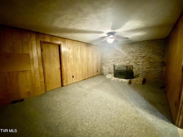 158 Taylortown Rd, Johnson City, TN 37601 - unfurnished living room featuring a wood stove, ceiling fan, a textured ceiling, carpet flooring, and wooden walls