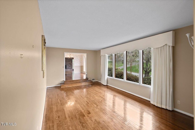 909 Millercrest Dr, Johnson City, TN 37604 - unfurnished living room with a chandelier, wood finished floors, baseboards, and visible vents