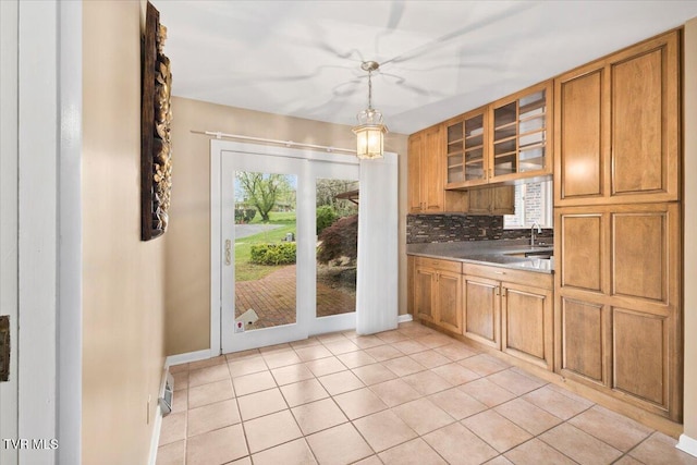 909 Millercrest Dr, Johnson City, TN 37604 - kitchen featuring tasteful backsplash, light tile patterned floors, glass insert cabinets, brown cabinetry, and hanging light fixtures