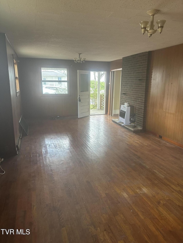 714 Fairview Ave, Kingsport, TN 37660 - unfurnished living room featuring a chandelier, hardwood / wood-style floors, wood walls, and a wood stove