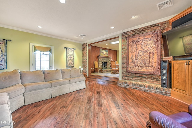 216 Forest Hills Dr, Bristol, TN 37620 - living room featuring brick wall, visible vents, ornamental molding, and wood finished floors