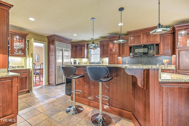 216 Forest Hills Dr, Bristol, TN 37620 - kitchen with black microwave, glass insert cabinets, backsplash, a kitchen bar, and hanging light fixtures