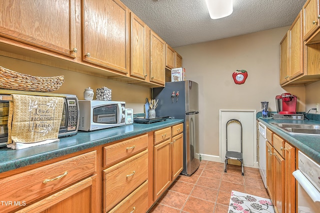 216 Forest Hills Dr, Bristol, TN 37620 - kitchen with light tile patterned floors, a textured ceiling, freestanding refrigerator, dark countertops, and a sink