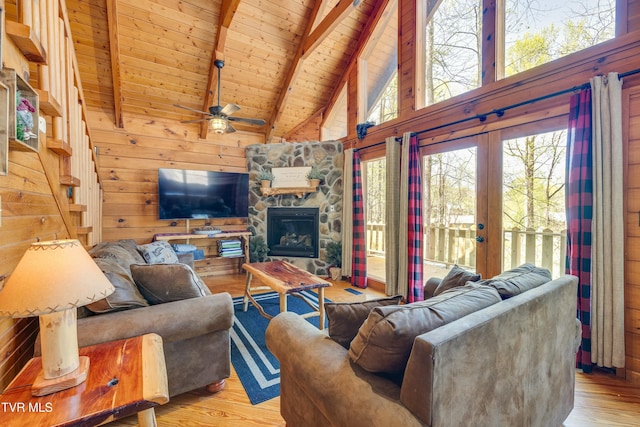 living area with light wood-style floors, ceiling fan, wooden ceiling, wooden walls, and beam ceiling