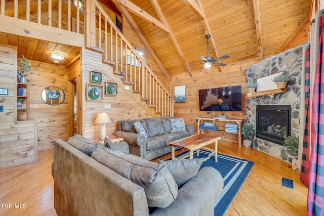 living area featuring a ceiling fan, wood walls, beamed ceiling, wood ceiling, and wood finished floors