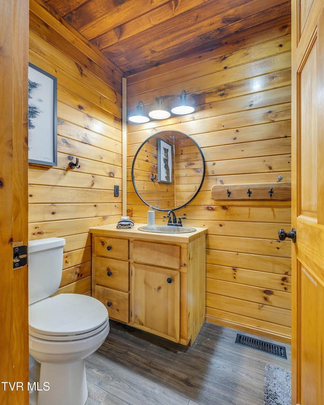 half bathroom with vanity, visible vents, toilet, wood ceiling, and wood finished floors