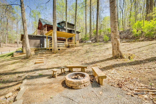 view of yard featuring a forest view, a fire pit, and stairs