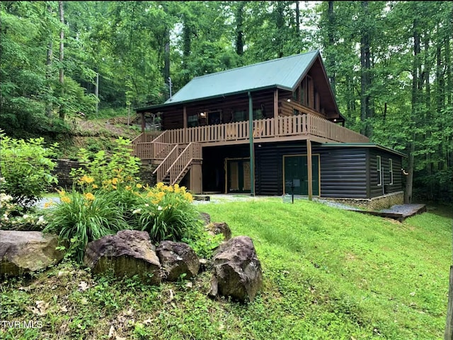 back of house featuring log siding, a wooded view, stairs, a wooden deck, and a yard