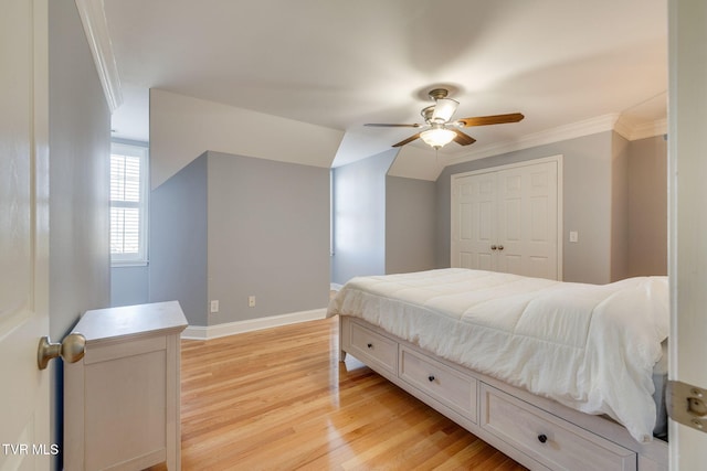 bedroom with crown molding, light wood-style flooring, a closet, vaulted ceiling, and baseboards