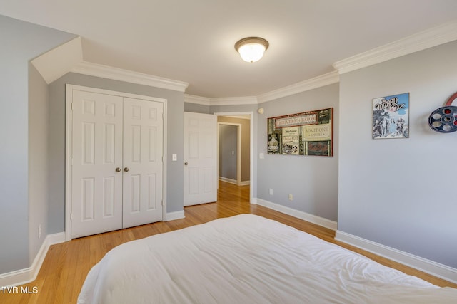bedroom featuring wood finished floors, ornamental molding, baseboards, and a closet